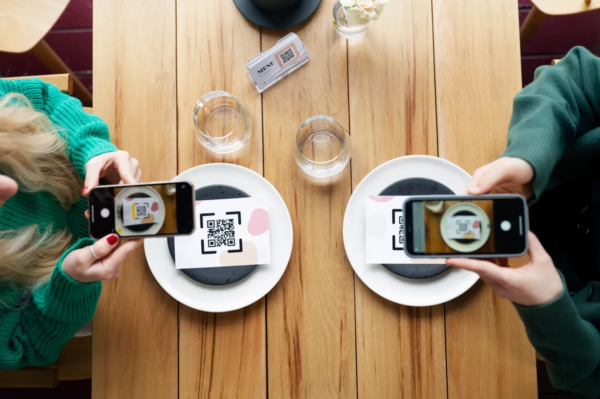 Restoran masasında QR kod ile telefondan sipariş veren müşteri